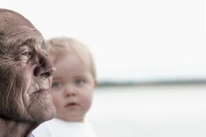 photo of old man with baby in the background looking at him
